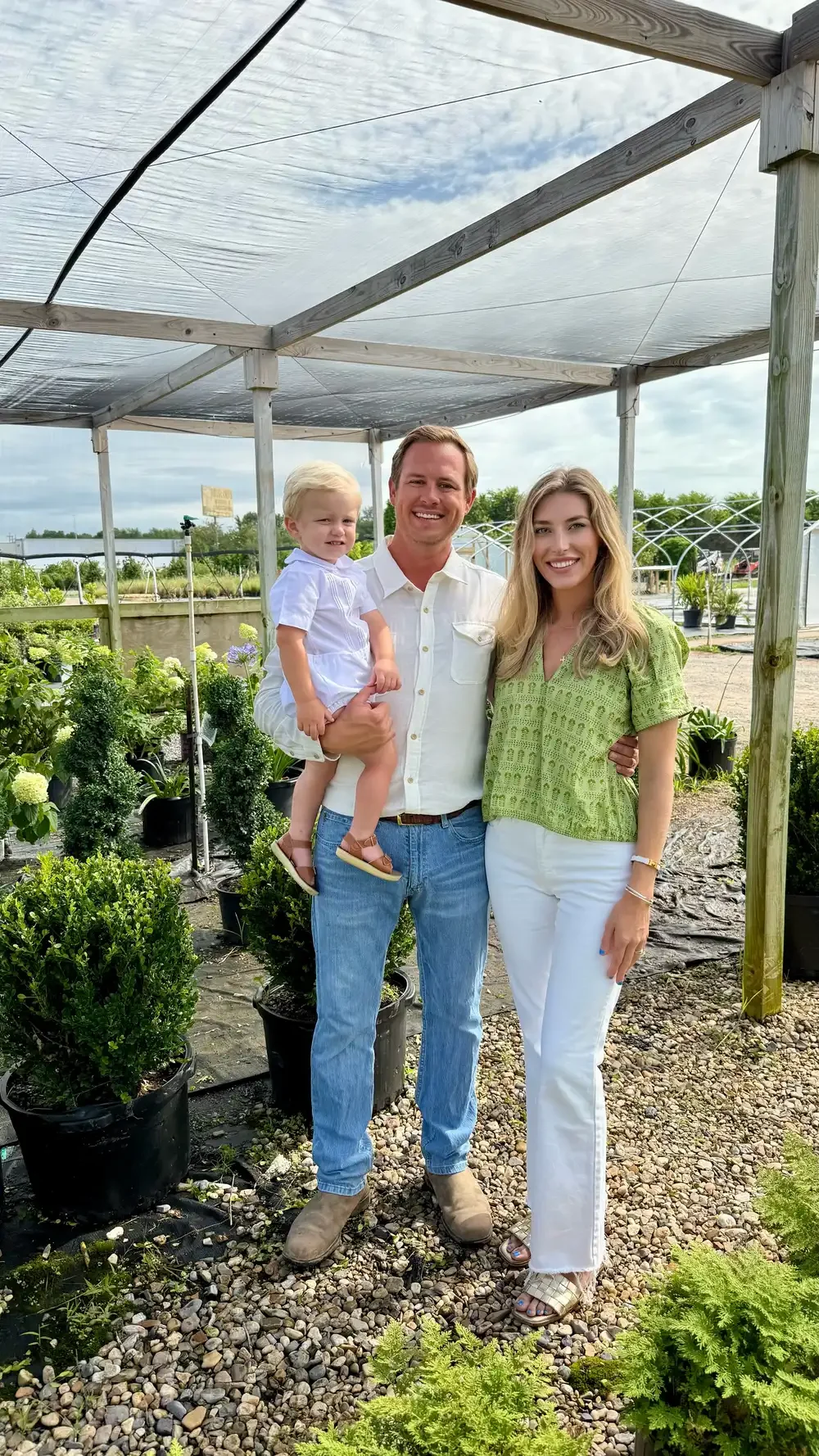 Family portrait of John and Carlyle Hoogland with their son Marshall, surrounded by greenery and landscaping plants, representing their commitment to family values and the legacy of Hoogland's Landscape.
