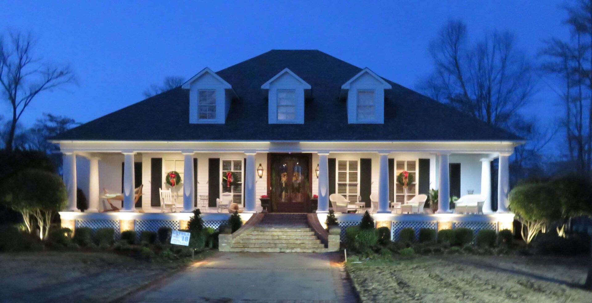 Elegant residential home adorned with holiday lighting, featuring wreaths on the front door and illuminated porch, showcasing Hoogland's custom holiday display.