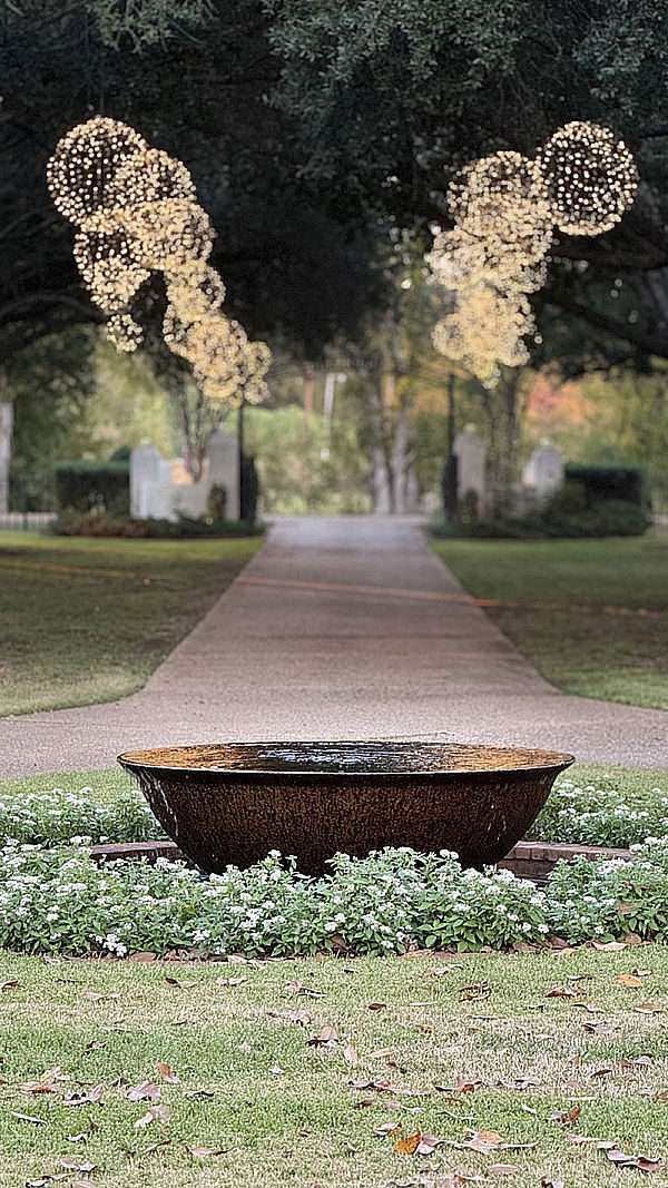Hooglands Holiday Lighting – 03 Pathway adorned with festive holiday lighting and a decorative water feature surrounded by greenery, enhancing the seasonal ambiance for Hoogland's Holiday Lights services.